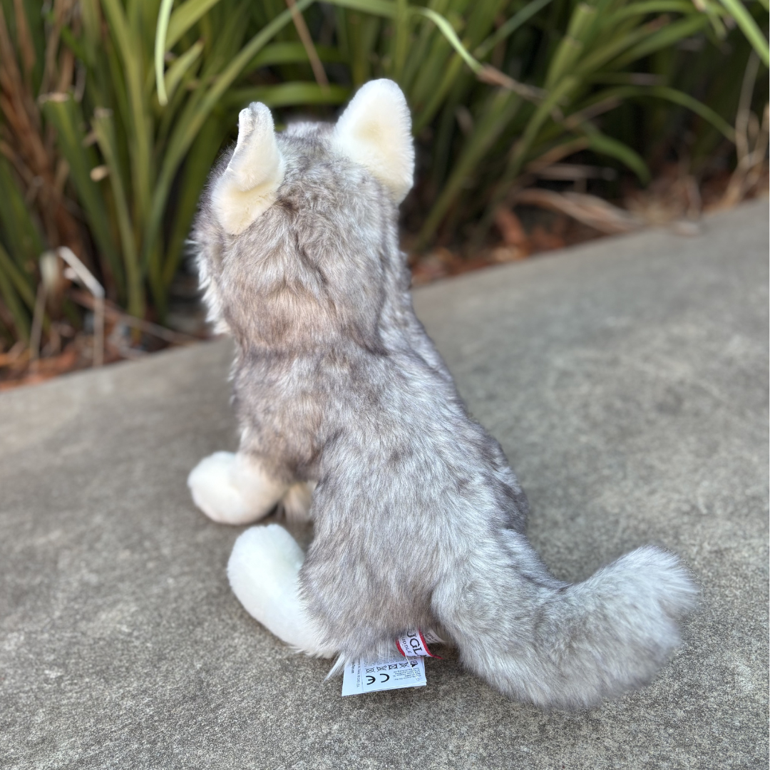 Shadow White Wolf by Douglas Dog back view sitting in front of green bushes