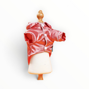 A shiny coral-pink hooded jacket displayed on a small cream-colored mannequin torso with a wooden neck cap, set against a plain white background.