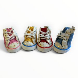 Four pairs of baby high-top sneakers lined up on a white background, featuring pink, yellow, red, and blue mesh uppers with gold rhinestone accents and white laces.