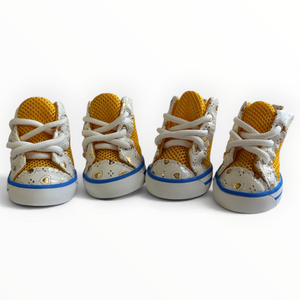 Four toddler high-top sneakers arranged in a row on a white background. The shoes feature a mustard yellow mesh upper, white speckled overlays, white laces, and a blue stripe along the white sole.