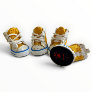 Four yellow and white high-top dog sneakers arranged on a white background, with one shoe lying on its side showing the black sole with a red paw print and the number 5.