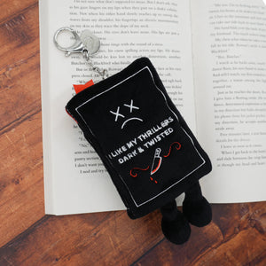 Black plush keychain with 'I like my thrillers dark & twisted' text on a book