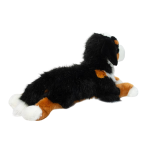 Plush toy dog with black, brown, and white fur on a white background