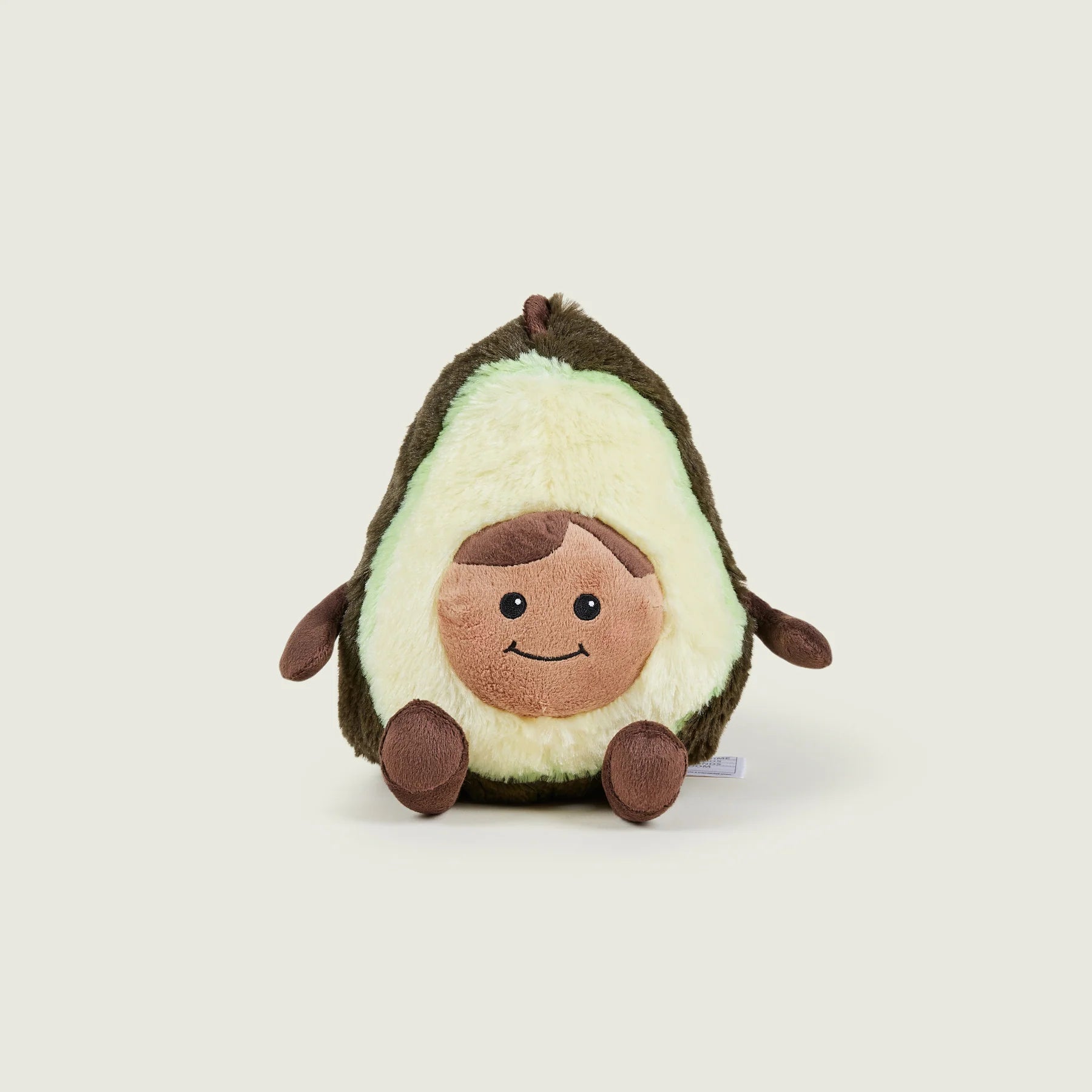 A plush avocado toy with a cute cartoon face, sitting upright on a light beige background.