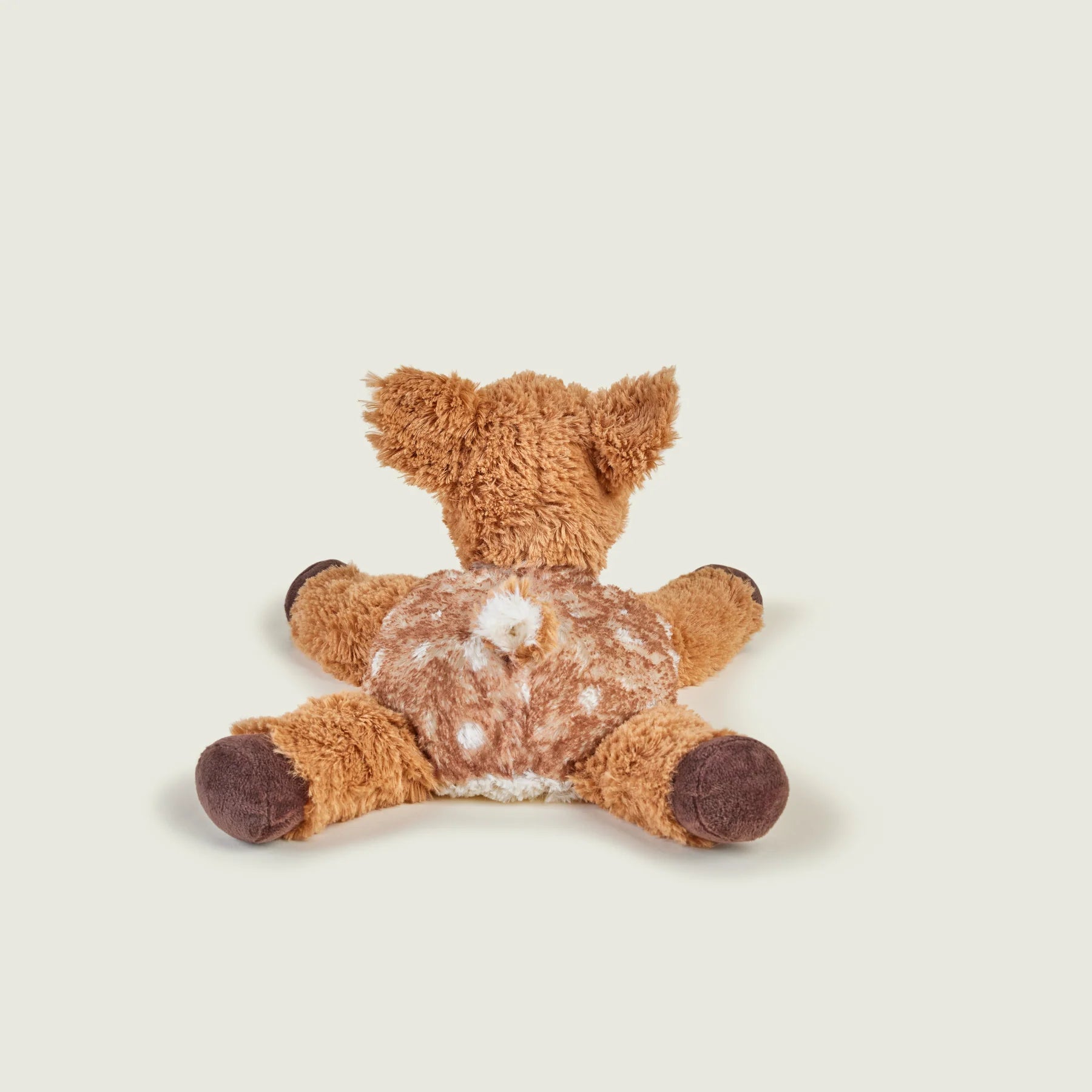 A plush stuffed toy shaped like a deer or rabbit, photographed from the back against a plain light warm-gray background.