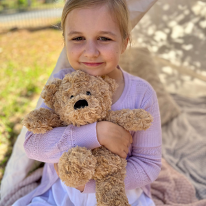 Girl holding a Bear plushie - Warmies brand - weighted, lavender scented heat bag - sensory toy