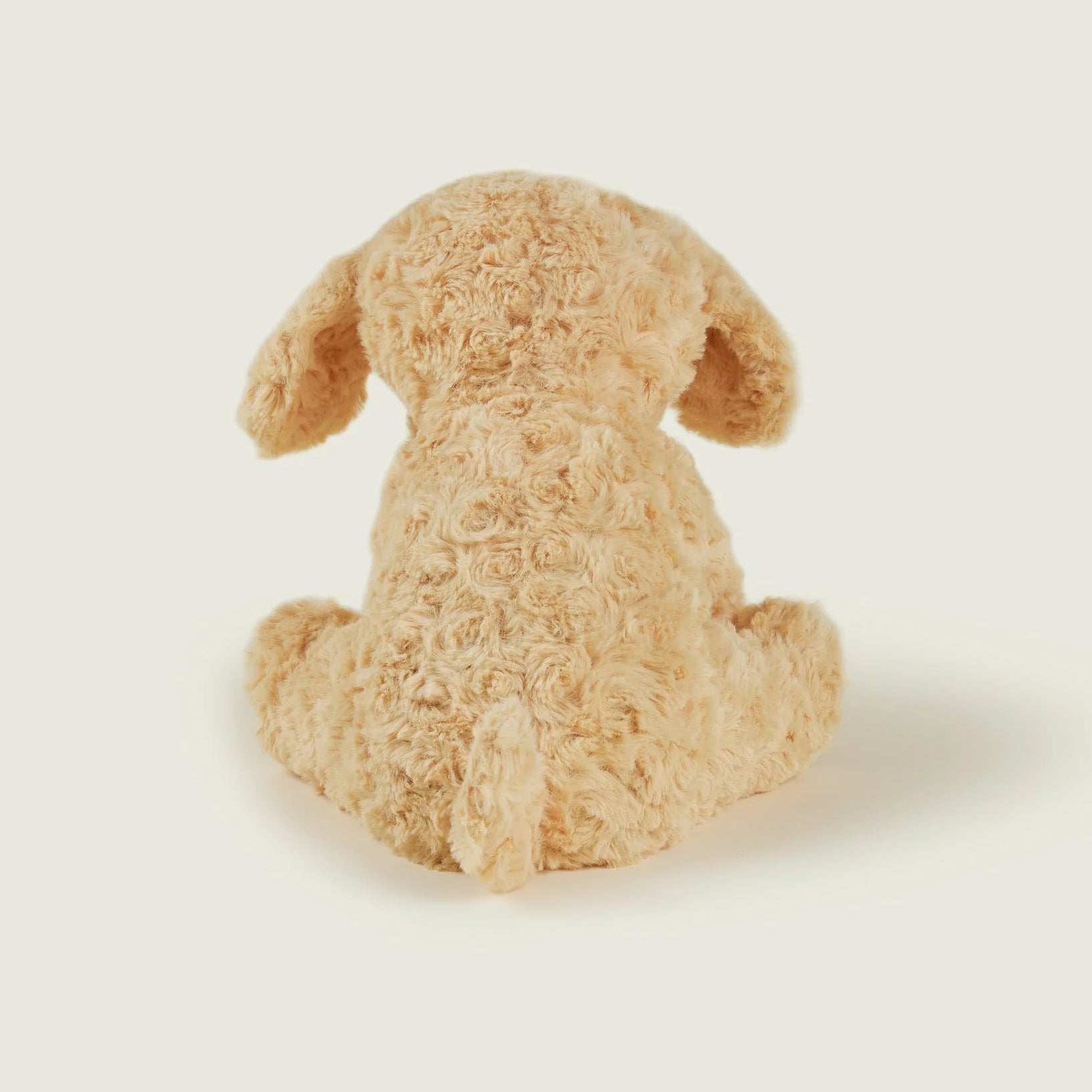 A light tan curly-haired plush dog toy shown from the back, sitting on a solid off-white background.