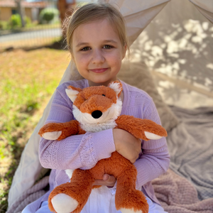 Girl holding Fox plushie - Warmies brand - weighted, lavender scented heat bag 