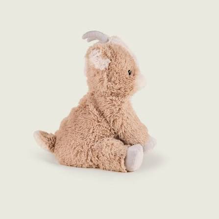 A plush stuffed animal shaped like a seated goat or sheep in a warm beige/tan color, with small pale gray horns and feet, photographed on a plain light beige background.