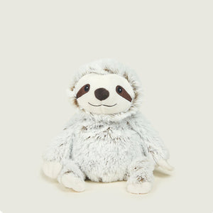 A plush sloth toy with fluffy light gray and white fur, a white face, and dark brown facial details, sitting against a plain light beige background.