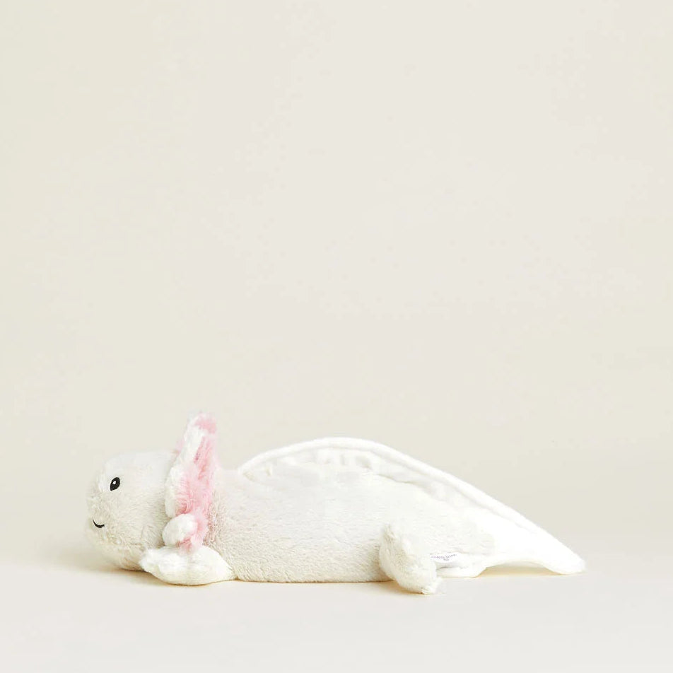A white plush axolotl toy with pink inner ears, lying on its side against a solid, warm off-white background.