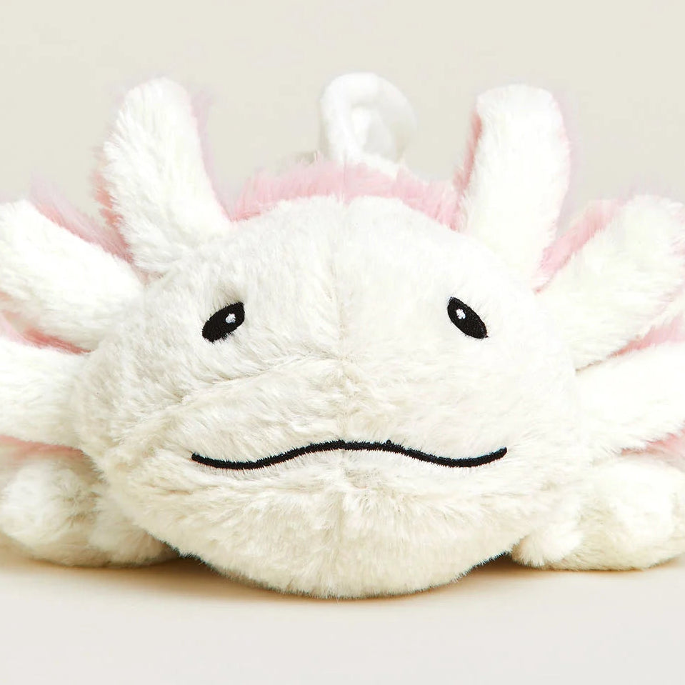 A white plush toy with pink accents and embroidered black facial features, photographed against a plain light beige background.