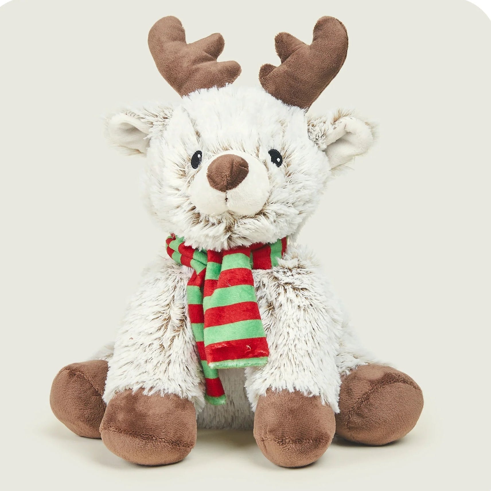 A plush stuffed reindeer toy with fluffy white fur, brown antlers, brown hooves, and a red and green striped scarf, sitting against a light beige background.