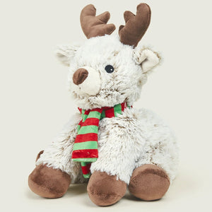 A white plush reindeer toy with brown antlers, hooves, and snout, wearing a red and green striped scarf, photographed against a light warm gray background.