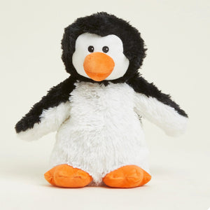 A plush penguin toy with black and white fur, a bright orange beak, and orange feet, photographed against a plain light beige background.