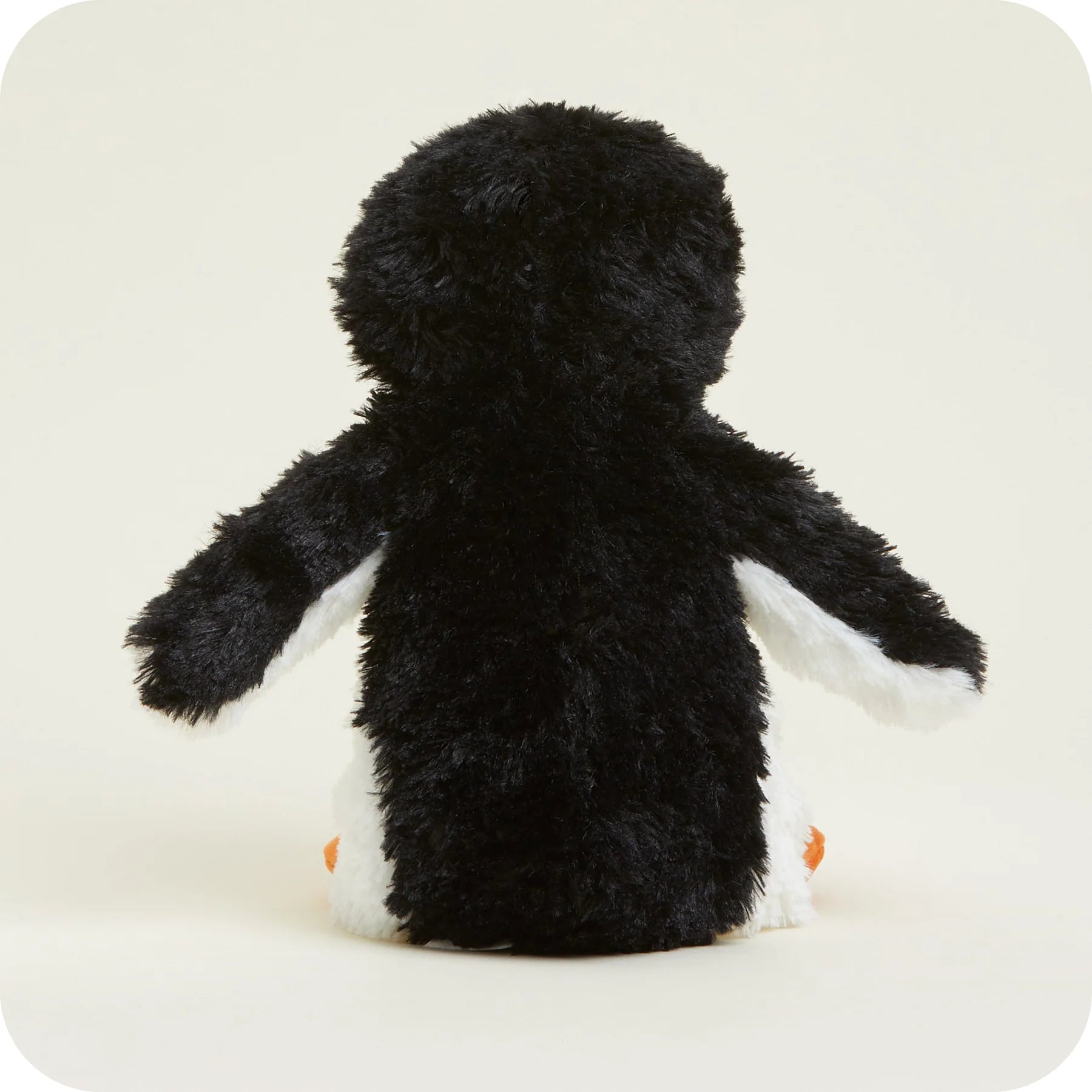 A plush penguin toy shown from the back, featuring black shaggy fur, white wings and feet, and small orange beaks, set against a plain off-white background.