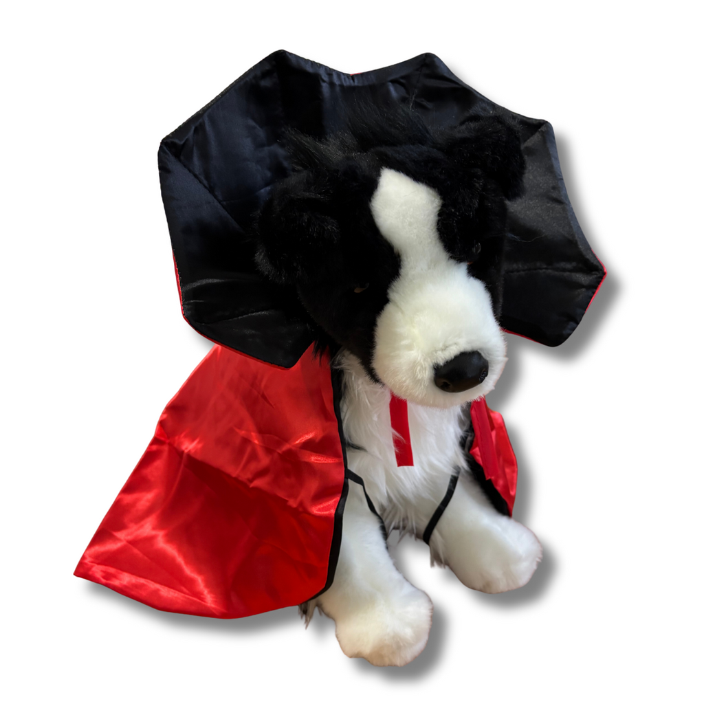 Stuffed dog toy with a black and red cape on a white background