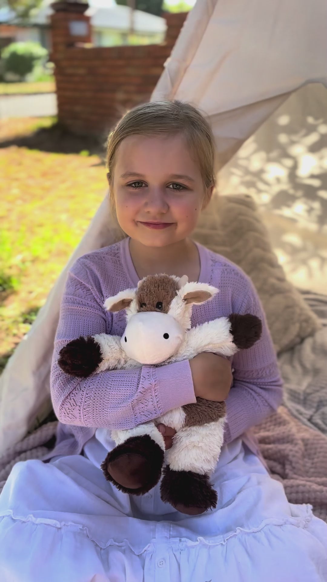girl holding a Cow plushie - Warmies brand - weighted, lavender scented heat bag video