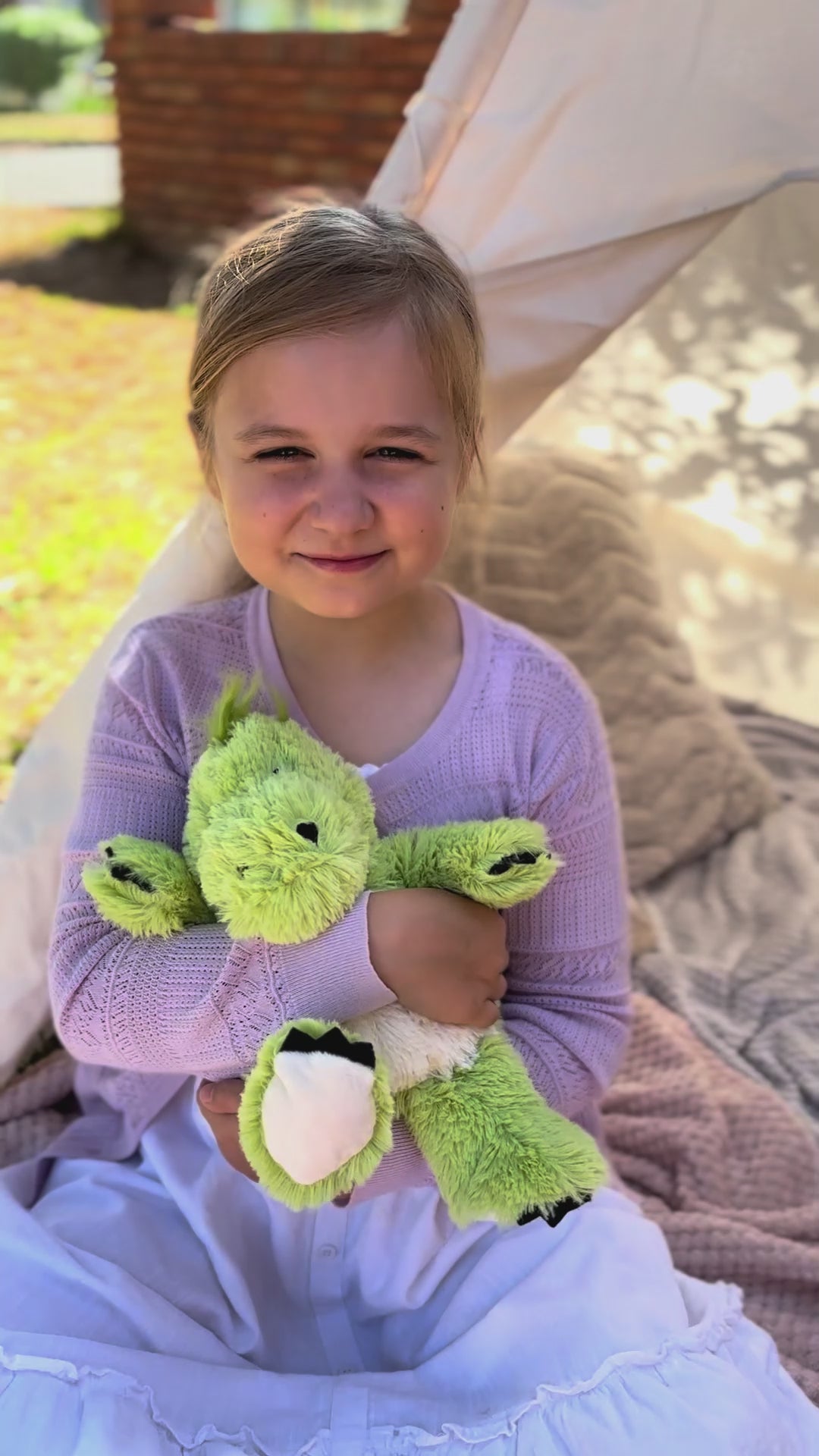 Girl hugging the green dinosaur plushie Warmies brand - weighted, lavender scented heat bag video