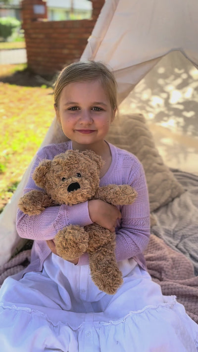 Girl holding a Bear plushie - Warmies brand - weighted, lavender scented heat bag 