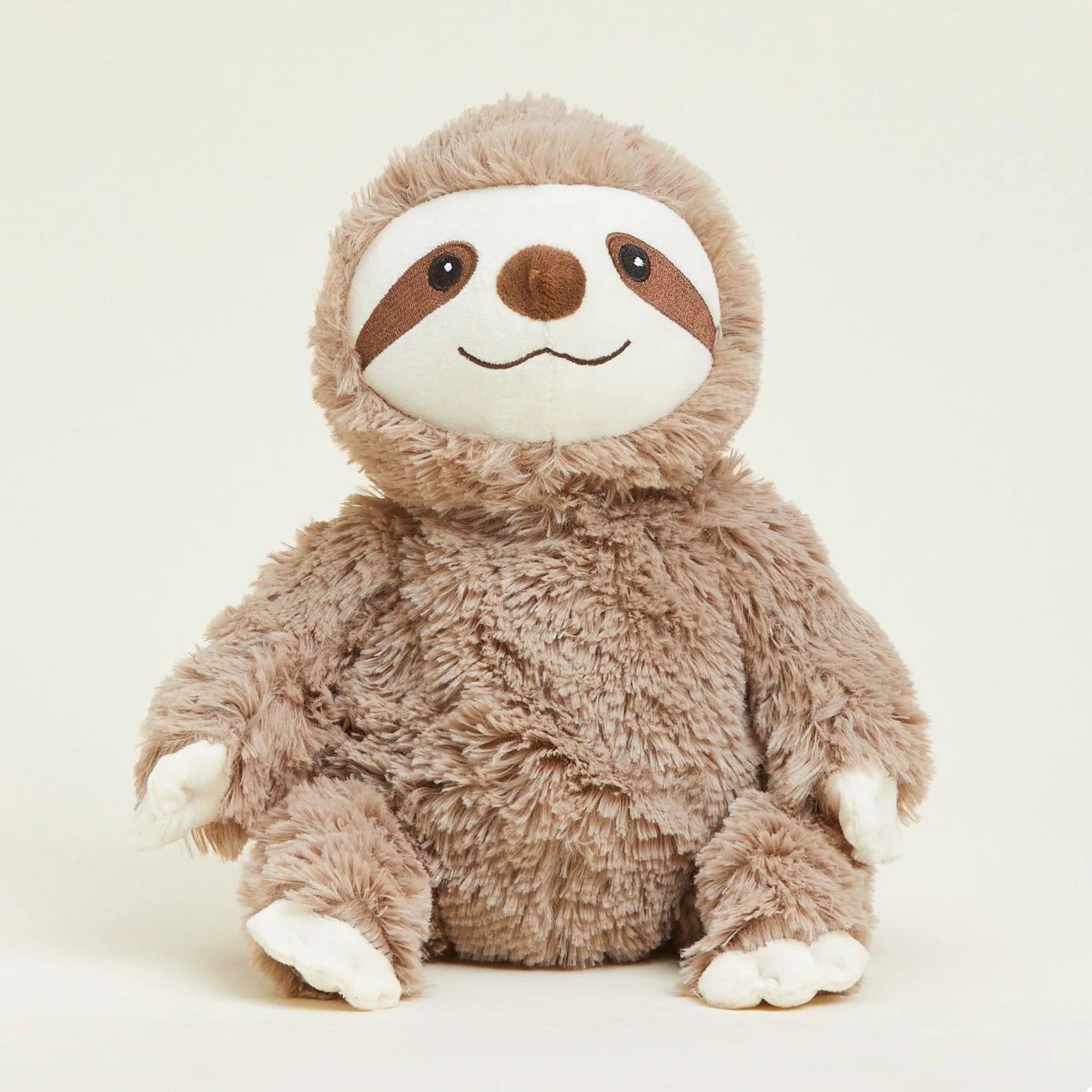 A plush sloth toy with shaggy brown fur, a white face, and brown facial markings, sitting against a plain light beige background.